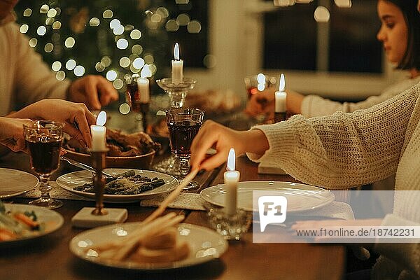 Glückliche Großfamilie mit vielen Kindern  die Weihnachten oder Silvester zusammen in einem gemütlichen  warmen Haus feiern und sich um einen festlichen Tisch mit köstlichen traditionellen Weihnachtsgerichten versammeln