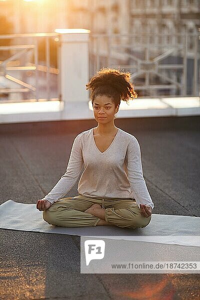 Ausgeschnittenes Foto einer Frau  die im Lotussitz auf einer Matte sitzt und Yoga praktiziert  eine Frau  die die Namaste Geste macht  während sie im Freien meditiert. Meditation und Achtsamkeit Konzept