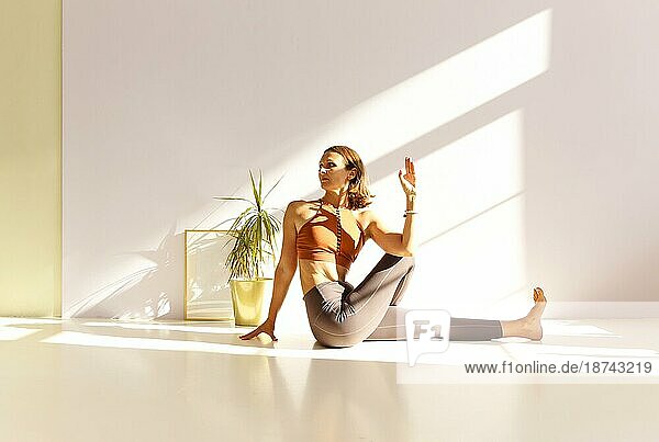 Seitenansicht einer ruhigen Frau in Sportkleidung  die Yoga in der Firefly Pose praktiziert  während sie mit den Armen auf der Matte balanciert und wegschaut