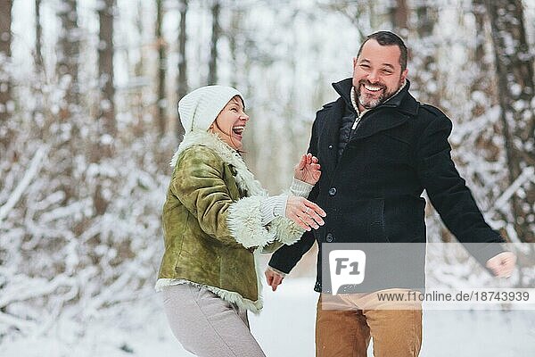 Lovely glücklich mittleren Alters Familie Paar Spaß im Freien in der Wintersaison Urlaub zusammen  wobei Spaziergang durch verschneite Wald mit Lächeln  in warme Kleidung gekleidet. Liebe und Freizeit Konzept