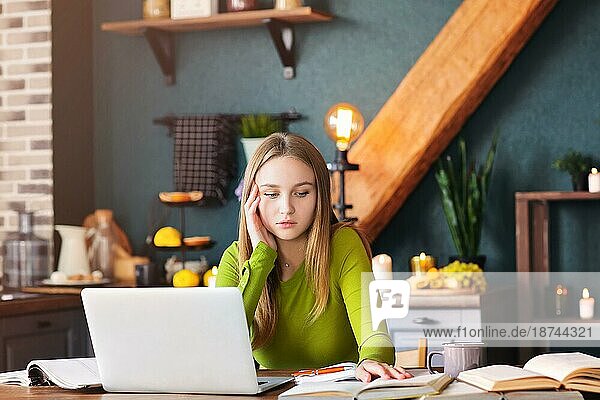 Junge nachdenkliche Frau Freiberufler sitzt am Tisch zu Hause mit Laptop  macht Notizen  starrt nachdenklich in die Luft  denkt über neue Ideen  weibliche Bloggerin auf der Suche nach Inspiration. Freiberufliches Konzept