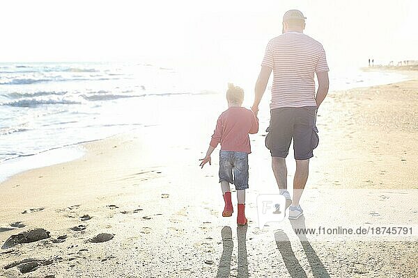 Liebevoller Vater spielt mit seiner entzückenden kleinen Tochter am Strand  Vater und Kind verbringen Zeit im Freien zusammen  sonniges Meer im Hintergrund. Parenting Konzept