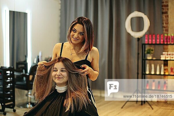 Professionelle Friseurin schmiert Farbstoff auf das Haar einer Frau bei der Arbeit im Schönheitssalon