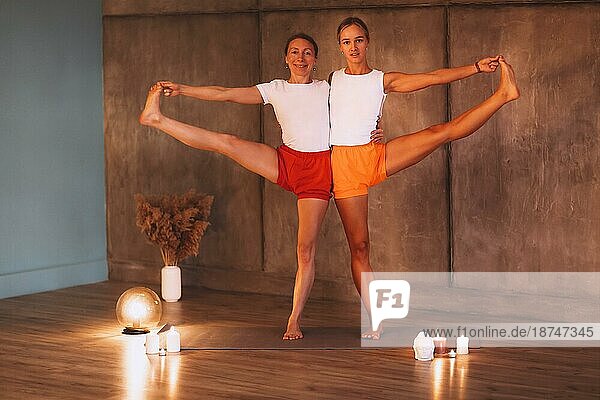 Zwei junge schlanke Frauen in bunten sportlichen trägt tun Yoga für Entspannung  attraktive Frauen Durchführung Stretching Übung. Sport indoor und gesunden Lebensstil