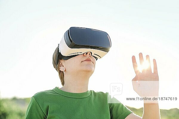Junge schöne schlanke Teenagermädchen trägt Virtual Reality Brille im Freien Natur Hintergrund. Smartphone mit VR Brille Headset im Sonnenuntergang