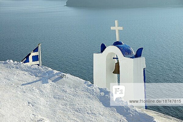 Ein Glockenturm und die griechische Fahne  gesehen auf Santorin