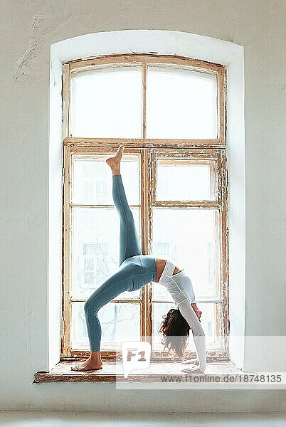 Seitenansicht einer ruhigen Frau in Sportkleidung  die Yoga in einer Pose praktiziert  während sie auf den Armen balanciert und wegschaut