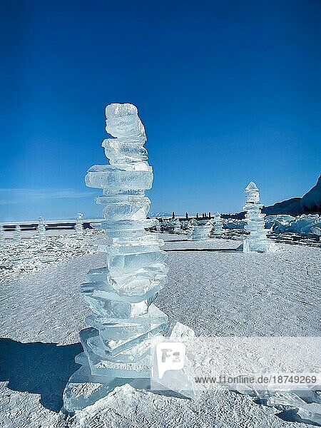 Eiswürfel auf dem idealen glatten Eis des Baikalsees mit Eishügeln am Horizont. Die Sonne scheint durch die Seiten der Eiswürfel. Die Schollen sehen aus wie Diamanten. Handgefertigte Pyramide