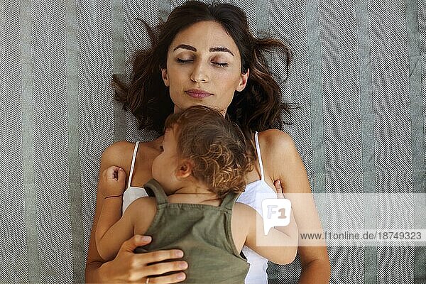 Mutterschaft Porträt. Blick von oben auf junge Frau Mutter mit niedlichen Baby an der Brust schlafen zusammen zu Hause am Tag  müde Mutter ruht auf Bett mit ihrem kleinen Sohn Kleinkind