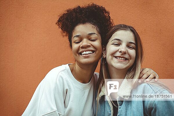 Porträt von zwei glücklichen  fröhlichen Teenagermädchen verschiedener Rassen  die in die Kamera lächeln und die Freundschaft genießen  multiethnische beste Freundinnen  die ein Selfiefoto machen und Spaß haben  während sie Zeit miteinander verbringen