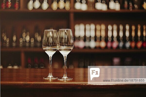 Zwei Gläser mit Weißwein auf dem hölzernen Stehtisch. Fotos in warmen Farben. Fokus auf das Glas Wein. Valentinstag  Datum  Liebe  Feier