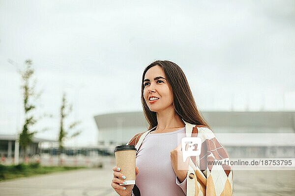 Ausgeschnittenes Foto einer zufriedenen jungen Frau mit einem Coffee to go Becher  die im Freien steht  eine glückliche Frau in einem warmen Pullover  die ein heißes Getränk in der Hand hält und einen schönen Spaziergang allein an einem Herbsttag genießt