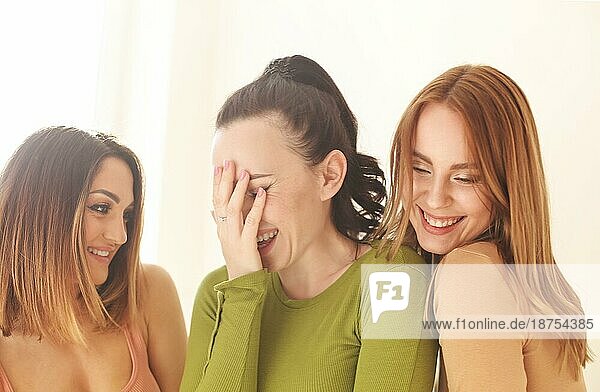 Gruppe fröhlicher erwachsener Frauen  die dicht beieinander stehen und hell lachen  in weichem Gegenlicht