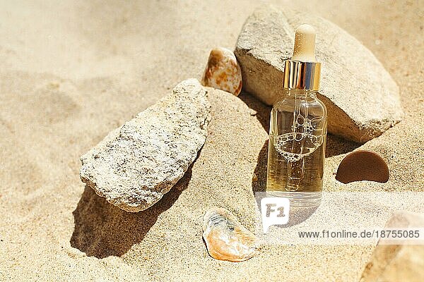 Draufsicht auf eine Flasche mit aromatischem ätherischem Öl in der Nähe von Steinen und Zweigen am Sandstrand