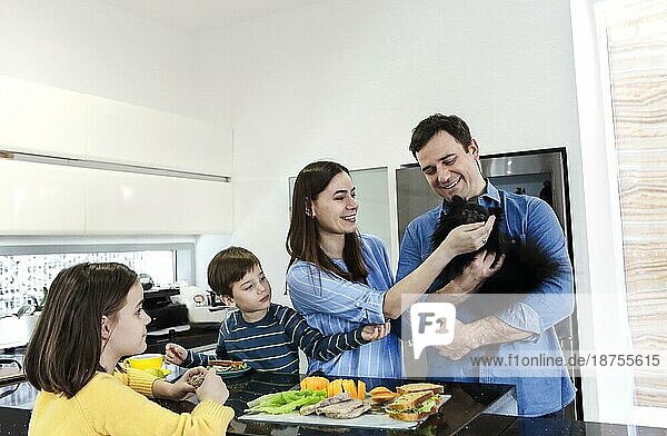 Happy Fröhlich Familie genießen gesundes Frühstück zusammen in der Küche zu Hause Wochenende mit kleinen lustigen Hund
