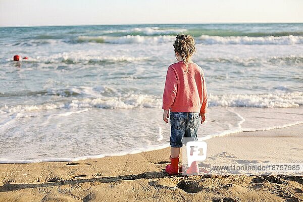 Süßes lächelndes kleines Mädchen  das am sonnigen Strand läuft  glückliches kleines Mädchen  das Zeit am Sommerstrand genießt. Rückansicht