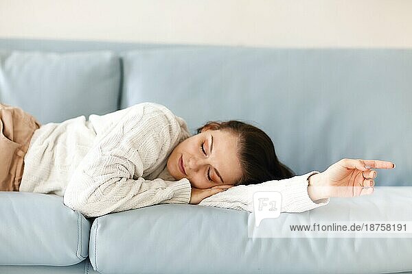 Close up von jungen kaukasischen Frau liegend auf blauem Sofa Indoor  schlief in lässigen Outfit müde von alltäglichen Aktivitäten  entspannend in gemütlichen gemütlichen Atmosphäre. Erholung Konzept