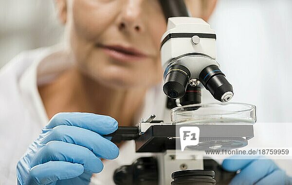 Unscharfe Wissenschaftlerin schaut durch ein Mikroskop