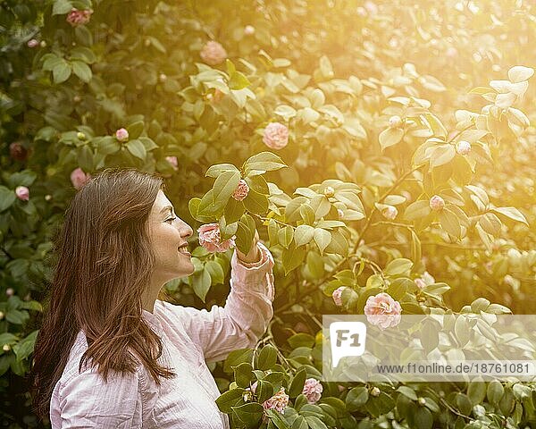 Attraktive glückliche Frau hält rosa Blume wächst grünen Zweig