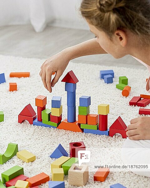 Nicht-binäres Kind spielt mit buntem Spiel zu Hause