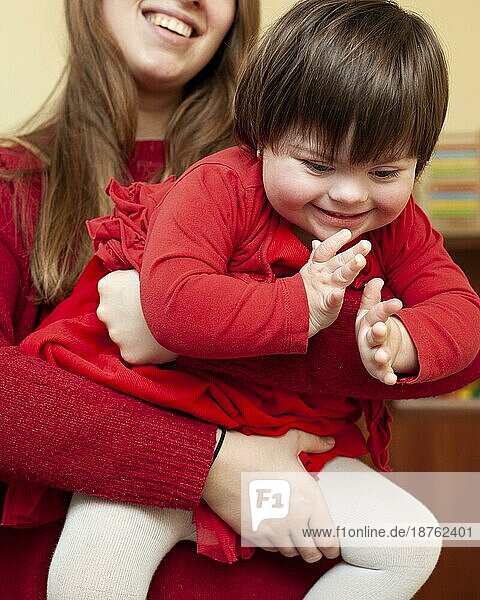 Frau hält glückliches Kind mit Down Syndrom