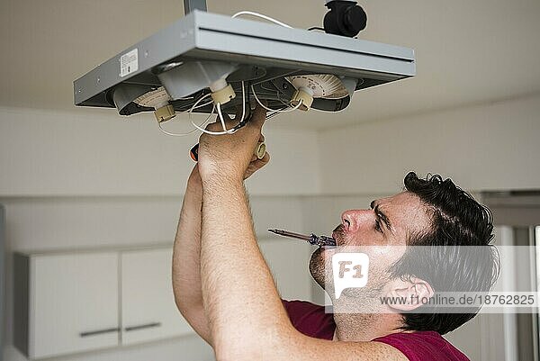 Mann trägt Tester Mund während der Reparatur der Decke Fokus Licht Hause