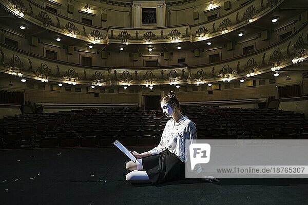 Seitenansicht weibliche Pantomime sitzend Bühne lesend Manuskript. Foto mit hoher Auflösung