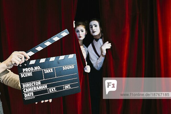 Person hält Klappe vor Pantomime Paar stehend roten Vorhang. Auflösung und hohe Qualität schönes Foto