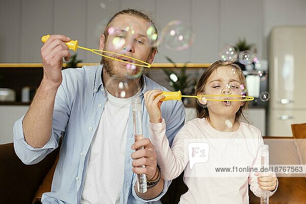 Vorderansicht Vater Tochter spielt mit Seifenblasen