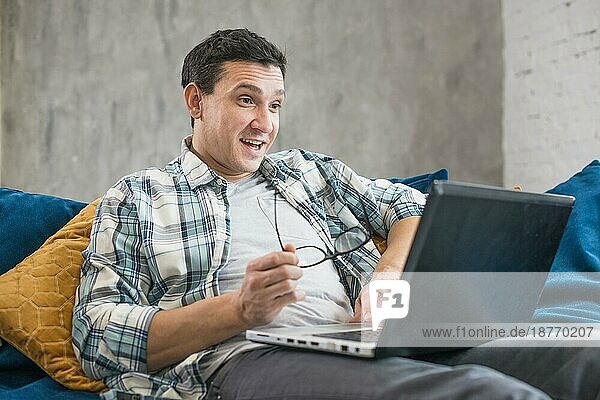 Überraschender Mann mit Laptop-Sofa