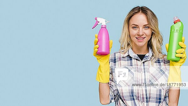 Vorderansicht glückliche Frau mit Blick in die Kamera  die eine Sprühflasche Waschmittelflasche hält