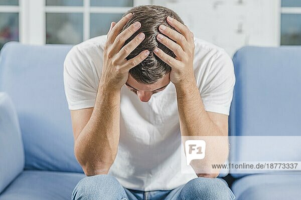 Frustrierter Mann mit Kopfschmerzen auf dem Sofa