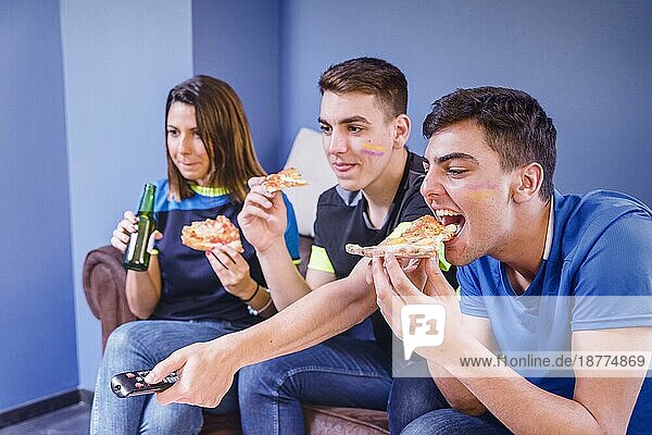 Fußballfans auf der Couch essen Pizza