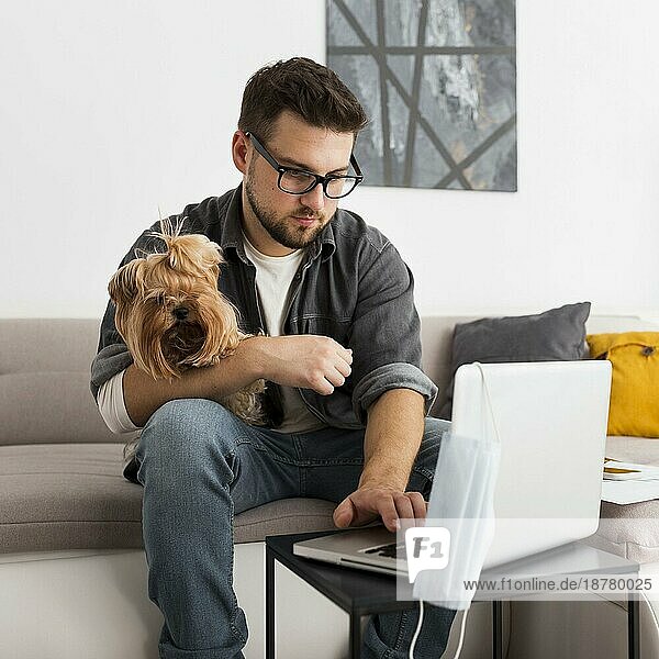 Porträt eines erwachsenen Mannes  der einen Hund hält  während er von zu Hause aus arbeitet