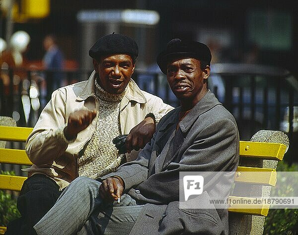 2 zwei junge Afrikaner sitzen auf einer auf einer Bank und reden miteinander