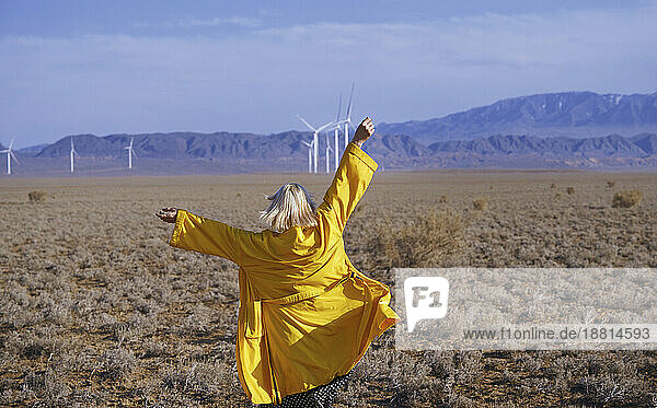 Blond woman with arms raised standing in desert