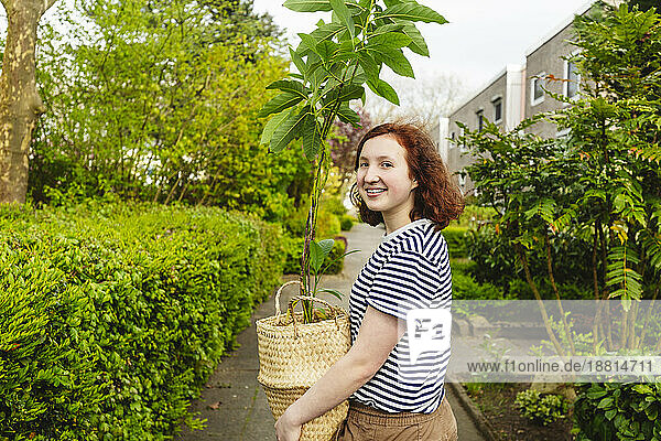 Smiling girl standing with avocado plant