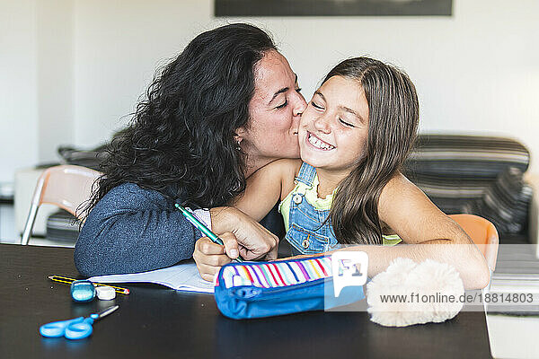 Mutter küsst Tochter  die Hausaufgaben macht