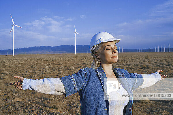 Engineer with arms outstretched and eyes closed standing in desert