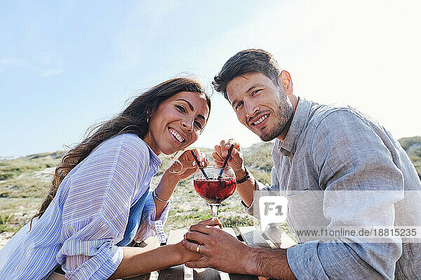 Happy couple sitting with glass of juice at table