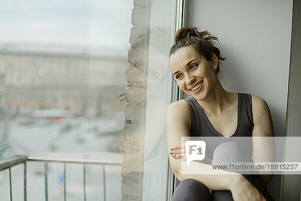 Happy woman leaning on glass window at home