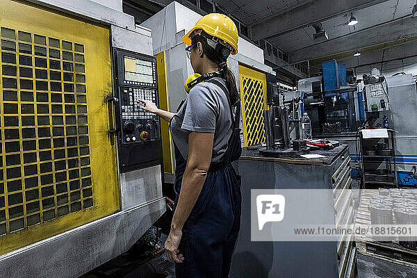 Maintenance engineer operating CNC Machine keypad in modern factory