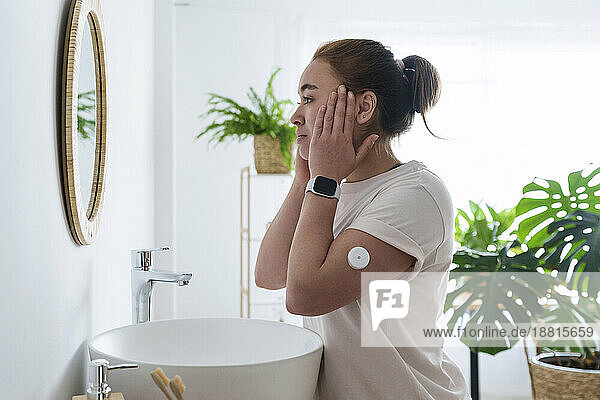 Frau mit Diabetes berührt Gesicht im Badezimmer zu Hause
