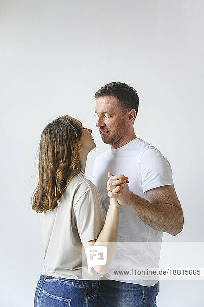 Romantic couple dancing against white background
