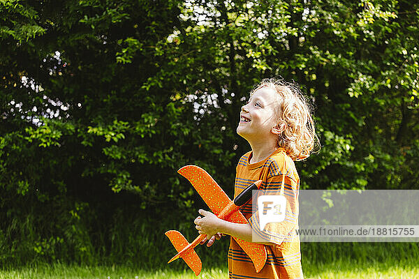 Lächelnder blonder Junge mit Flugzeugspielzeug im Park