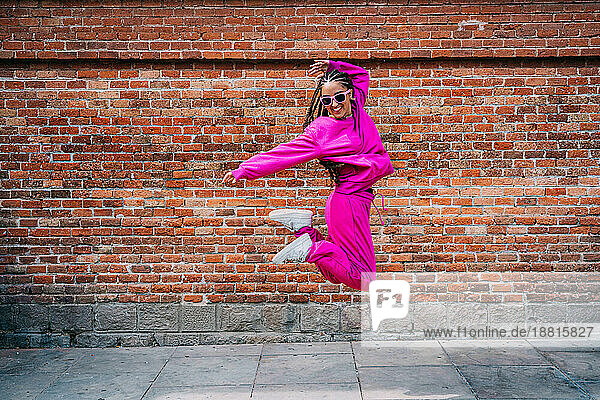 Fröhliche Frau springt vor einer Mauer