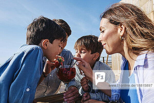 Glückliche Familie  die an einem sonnigen Tag gemeinsam Saft trinkt
