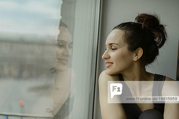 Smiling woman looking out of window at home