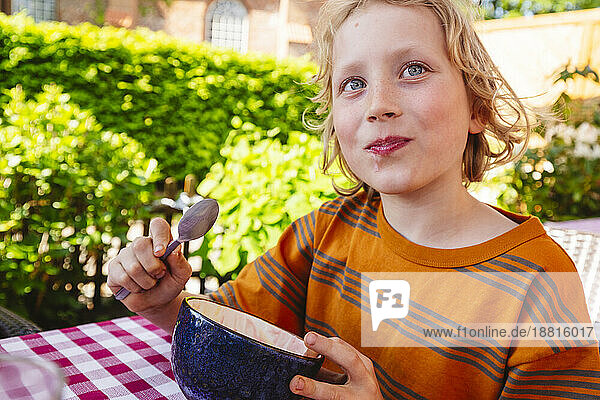 Blond boy eating desert in bowl
