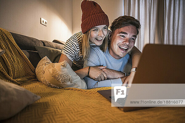 Liebevolles junges Paar benutzt Laptop im Wohnzimmer